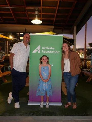Dr. Nader Nassif with fellow 2026 Jingle Bell Run honorees in front of an Arthritis Foundation banner